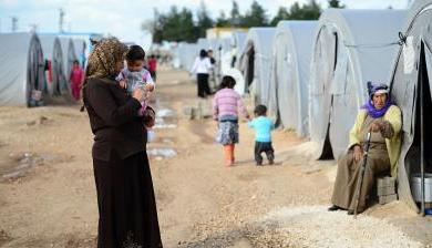 A woman stands holding her child at a Syrian refugee camp in Turkey.